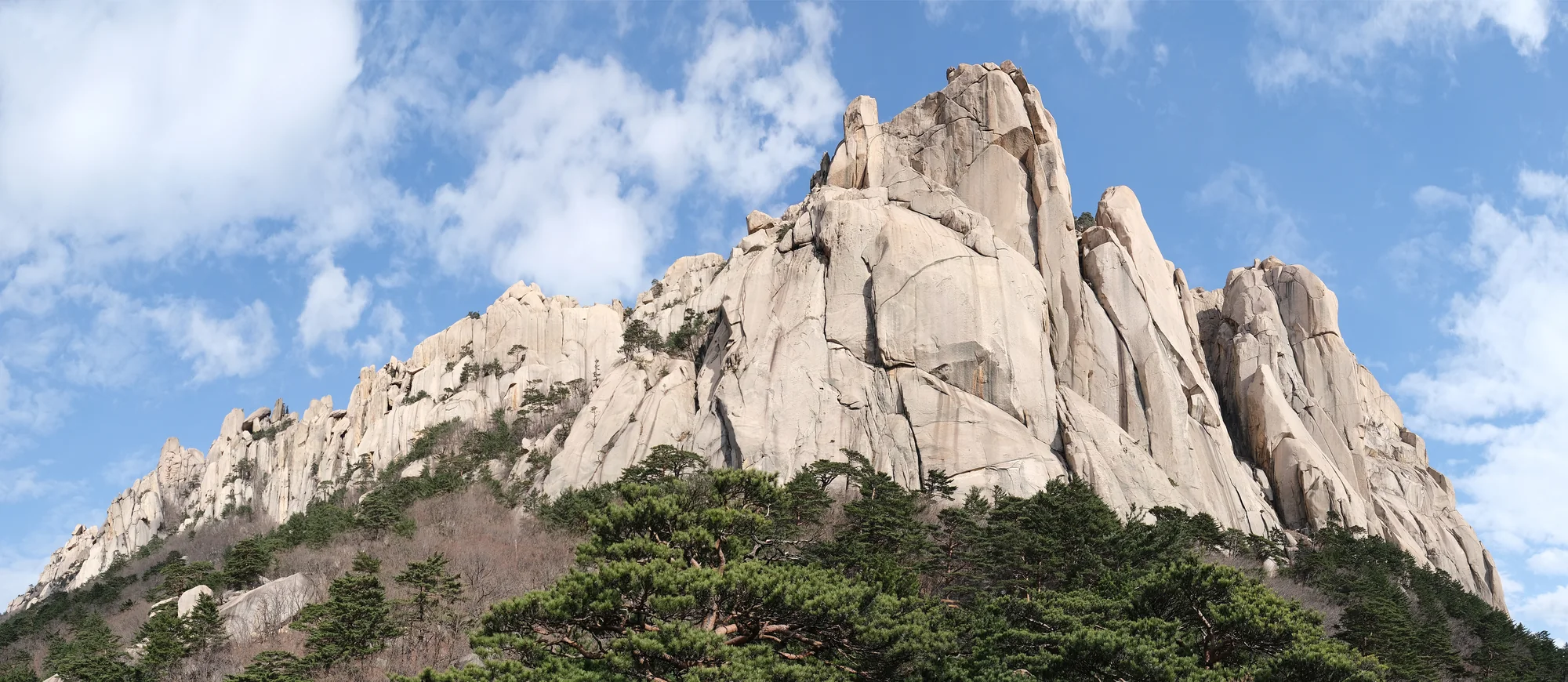 Sunlit granite towers of Ulsanbawi beneath blue sky and scattered clouds in Seoraksan National Park